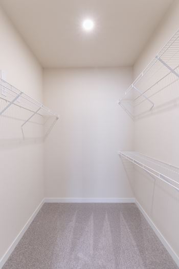 Empty walk in closet with white shelves.